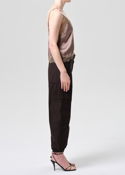 Person wearing a metallic top and dark pants on a grey background