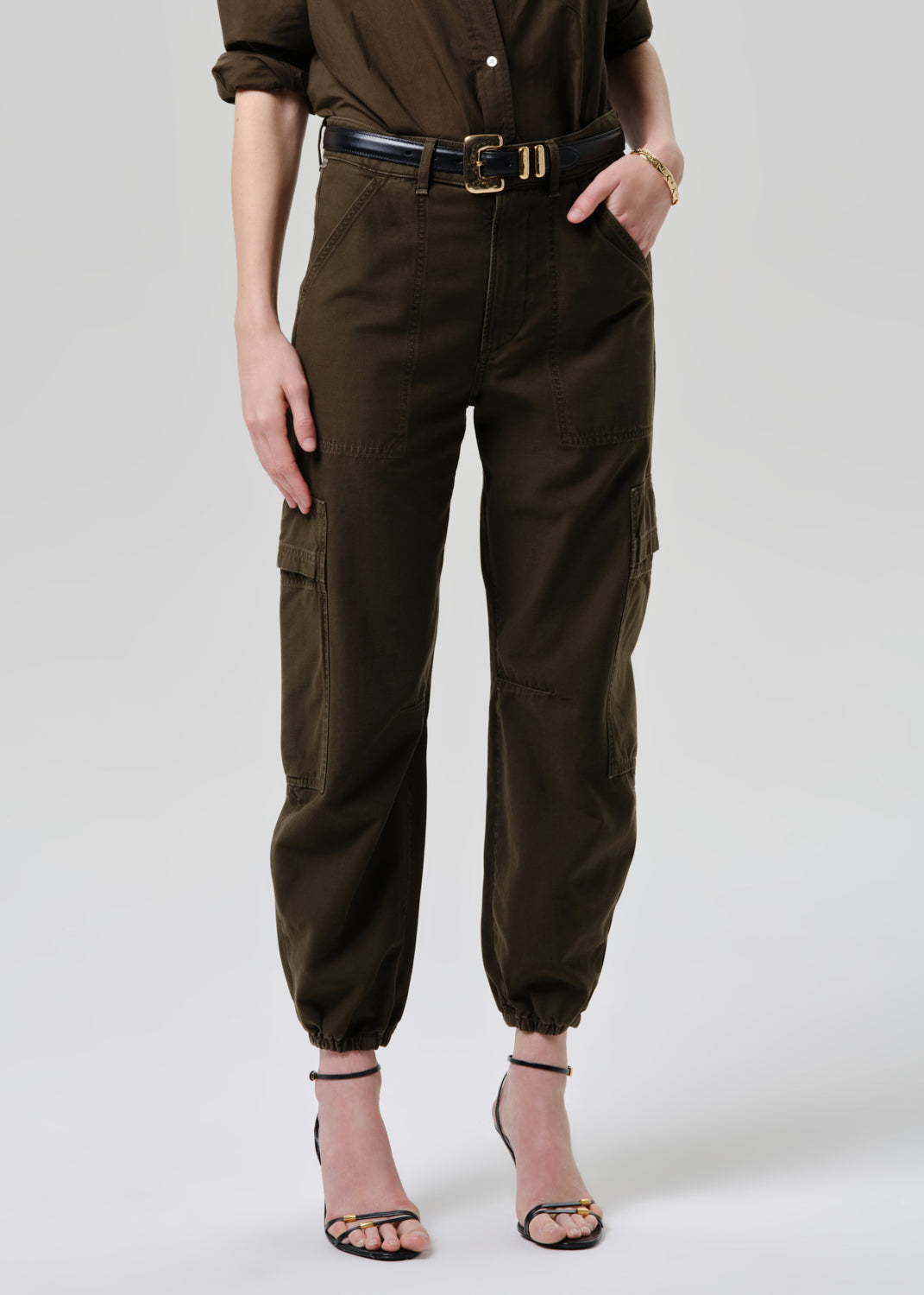 Person wearing brown cargo pants and a matching top on a grey background