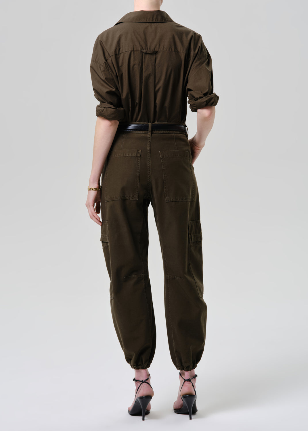 Person wearing a brown jumpsuit on a grey background