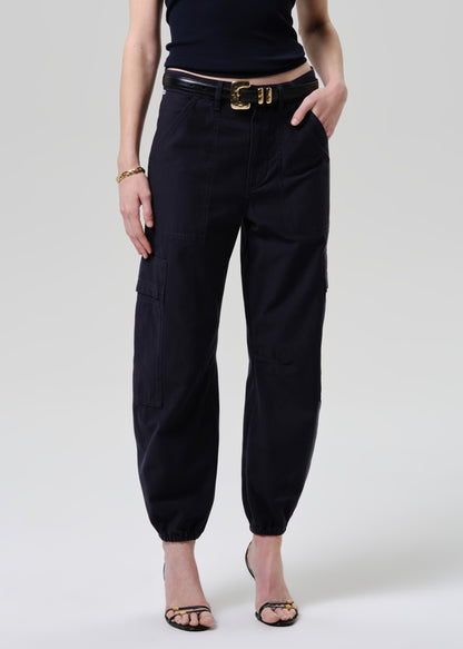 Person wearing black high-waisted pants with a belt on a grey background