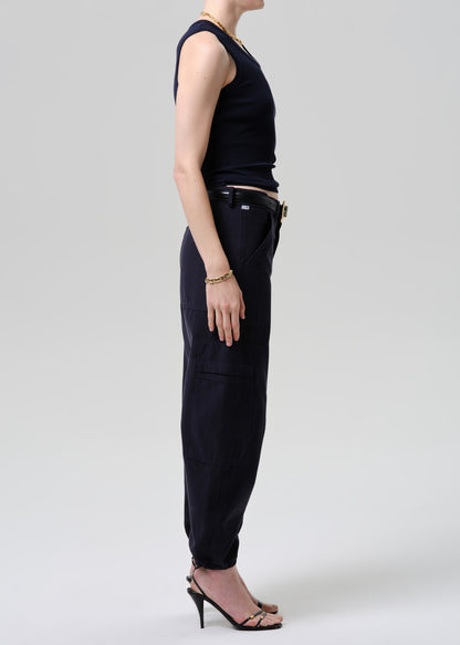 Person wearing a black sleeveless top and pants on a grey background