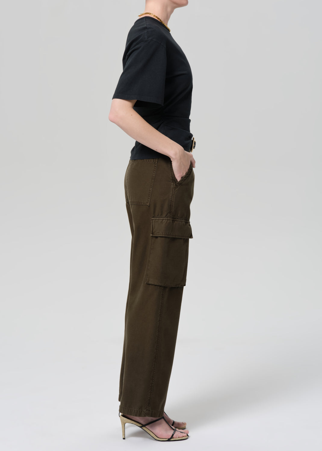 Person wearing a black t-shirt and green cargo pants on a light gray background