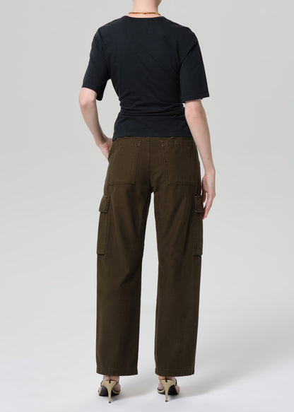 Person wearing a black t-shirt and green cargo pants on a light gray background