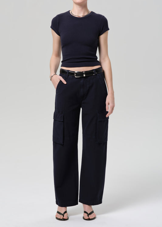 Person wearing a navy tee and navy cargo pants with a belt on a grey background