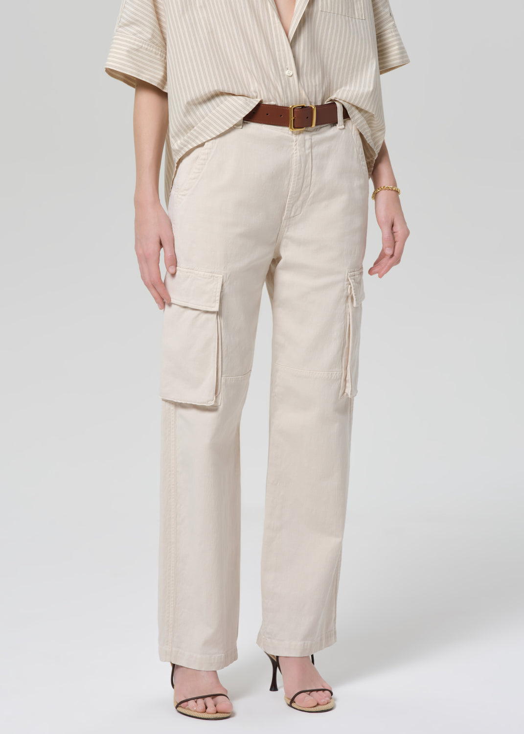 Person wearing beige cargo pants and a matching top on a grey background
