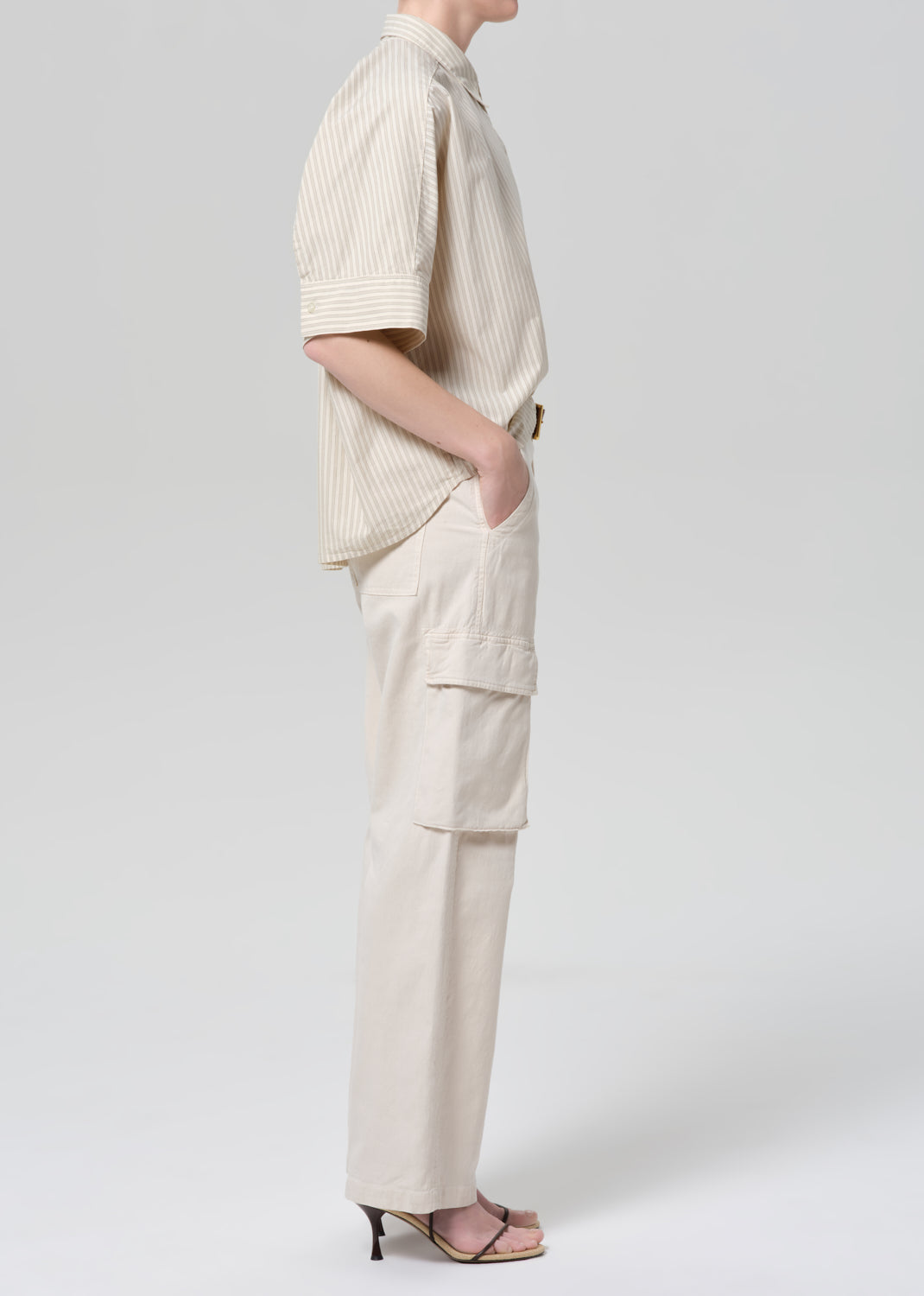 Person wearing a beige outfit with a shirt and cargo pants on a white background