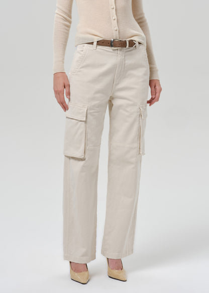 A model wearing a pair of off-white cargo pants with a brown belt, paired with a beige cardigan and beige heels, shown from the waist down on a grey  background.