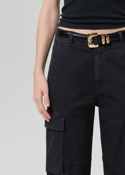 Person wearing a black tee with black cargo pants and a belt on a grey background