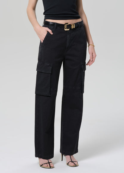 Person wearing a black tee with black cargo pants and a belt on a grey background