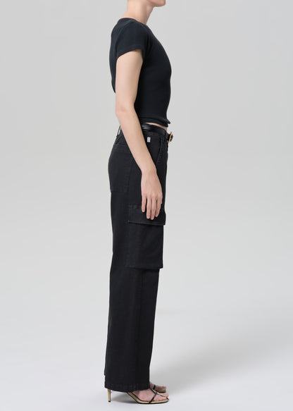 Person wearing a black tee with black cargo pants and a belt on a grey background