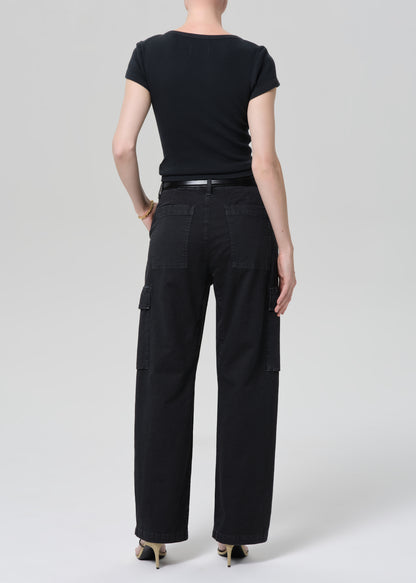 Person wearing a black tee with black cargo pants and a belt on a grey background