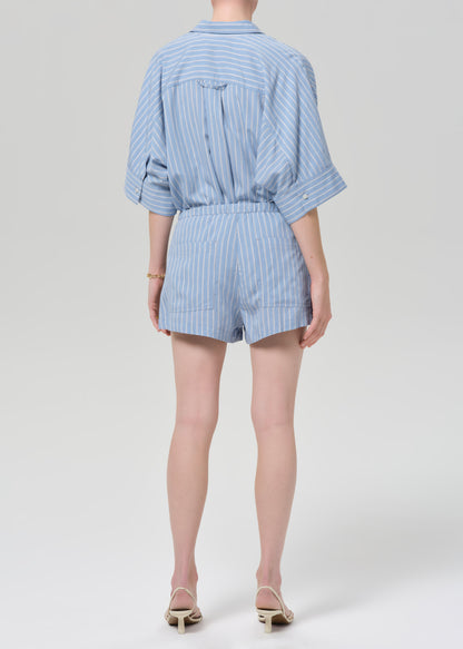Person wearing a blue striped shirt with matching shorts on a grey background