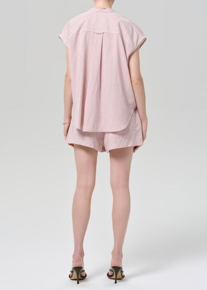 Person wearing a pink striped shirt with matching shorts on a grey background