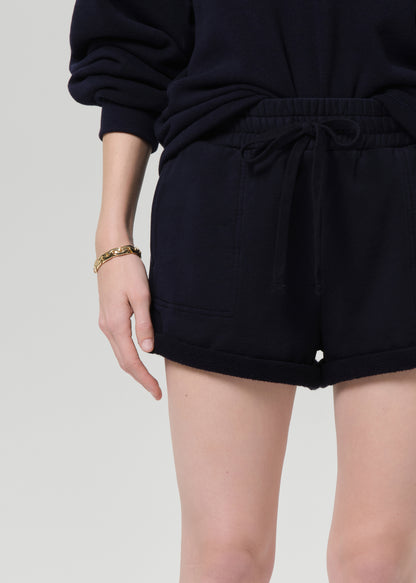 Person wearing a navy sweatshirt and shorts on a grey background