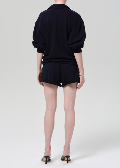 Person wearing a navy sweatshirt and shorts on a grey background