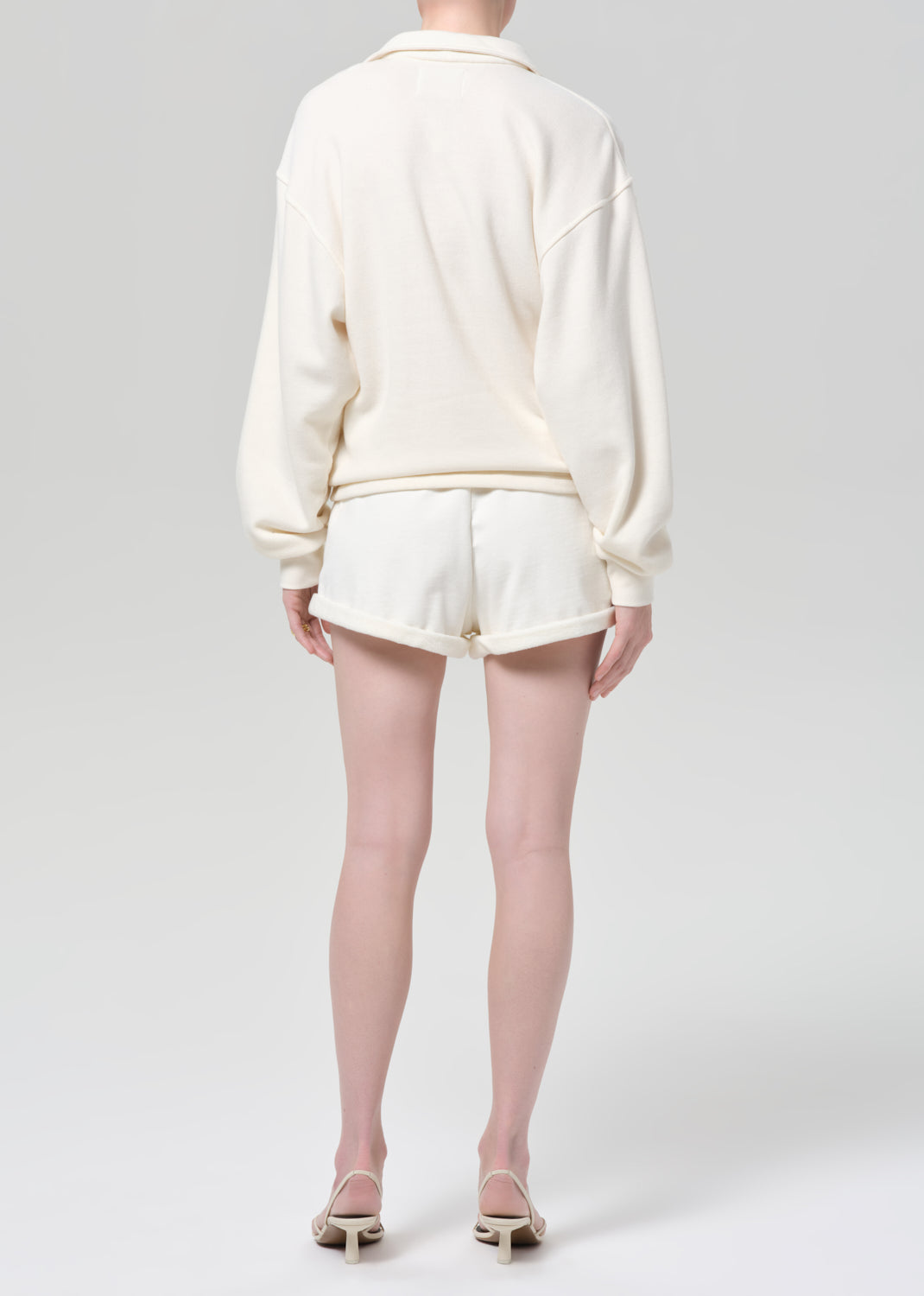 Person wearing a white outfit with shorts on a plain background