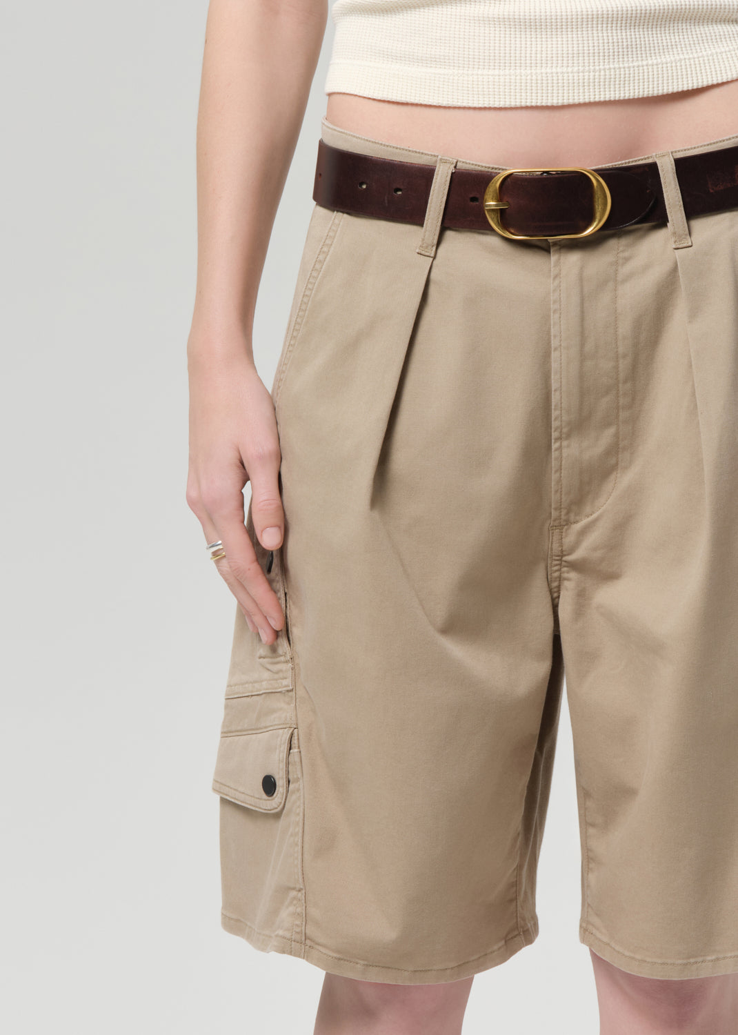 Person wearing a beige sleeveless top and beige cargo shorts on a grey background
