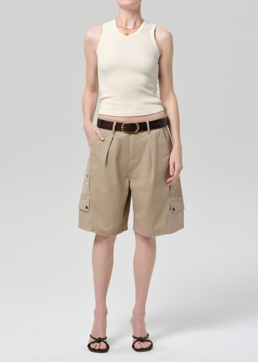 Person wearing a beige sleeveless top and beige cargo shorts on a grey background