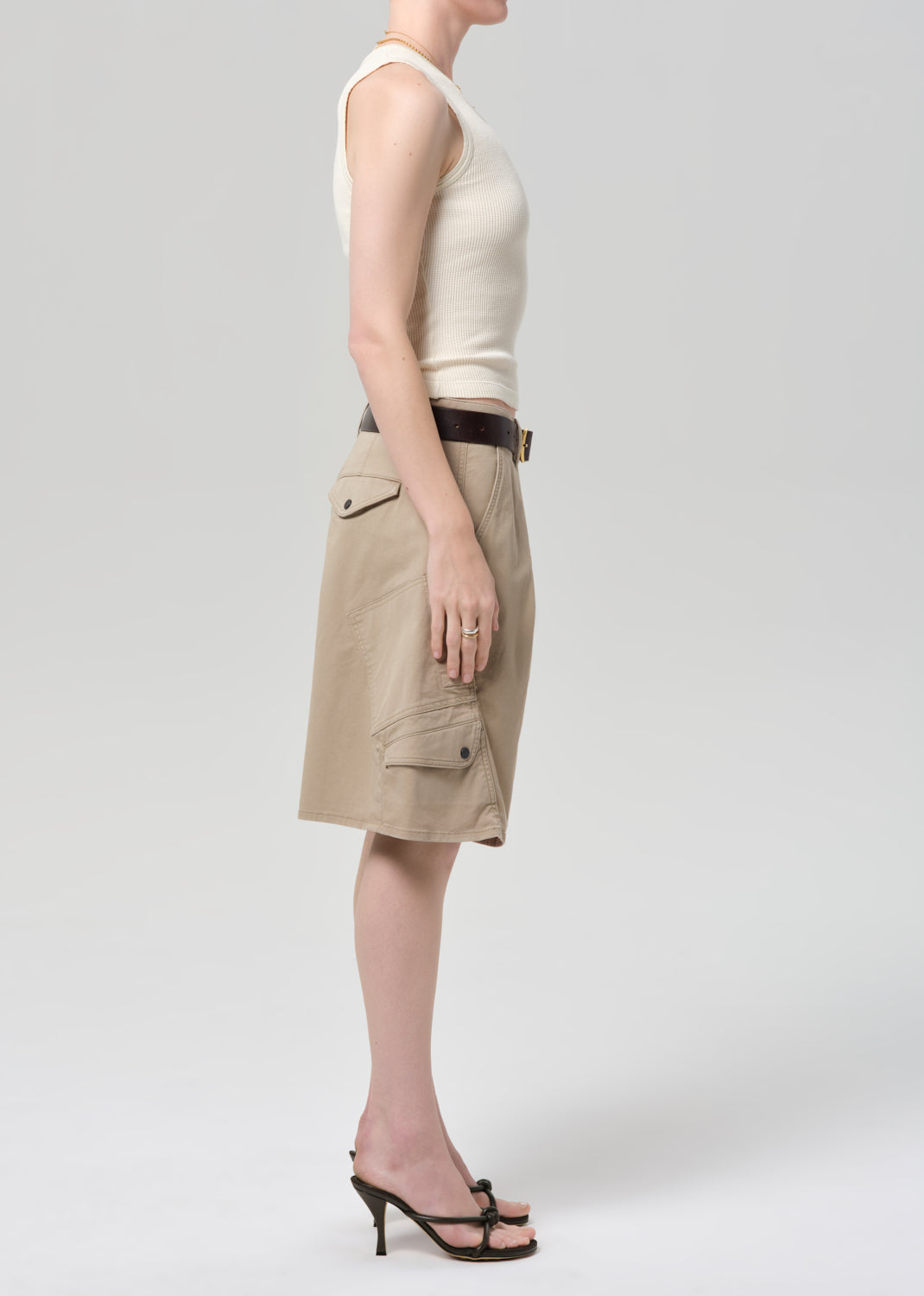 Person wearing a beige sleeveless top and beige cargo shorts on a grey background