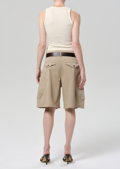 Person wearing a beige sleeveless top and beige cargo shorts on a grey background