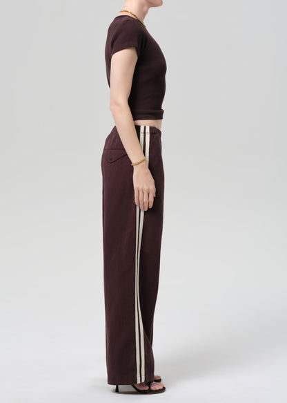 Person wearing a brown t-shirt and wide-leg pants with side stripes on a plain background