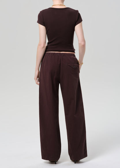 Person wearing a brown t-shirt and wide-leg pants with side stripes on a plain background
