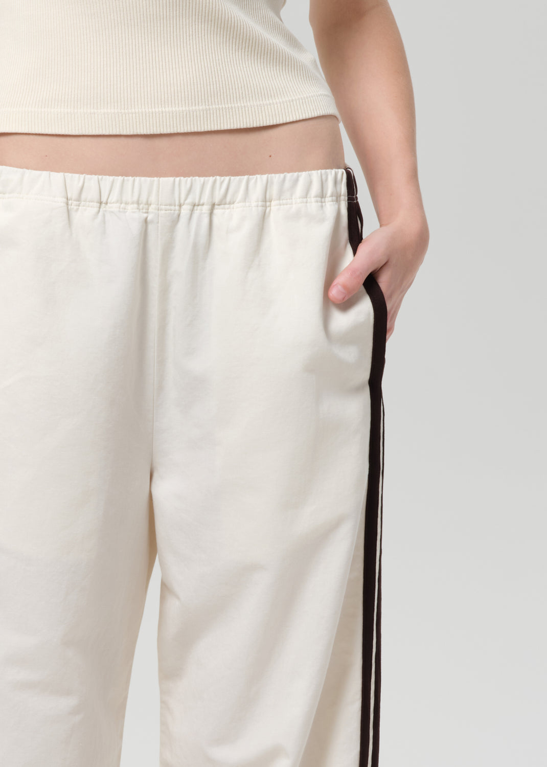 Person wearing a cream tank top and wide-leg pants with stripes on a plain background