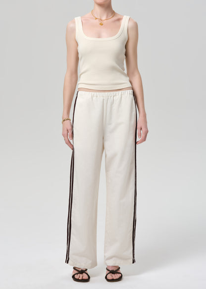 Person wearing a cream tank top and wide-leg pants with stripes on a plain background