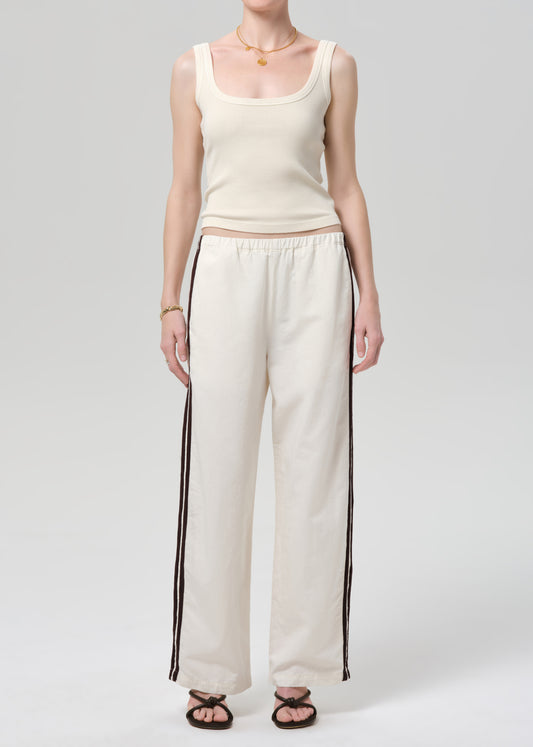 Person wearing a cream tank top and wide-leg pants with stripes on a plain background