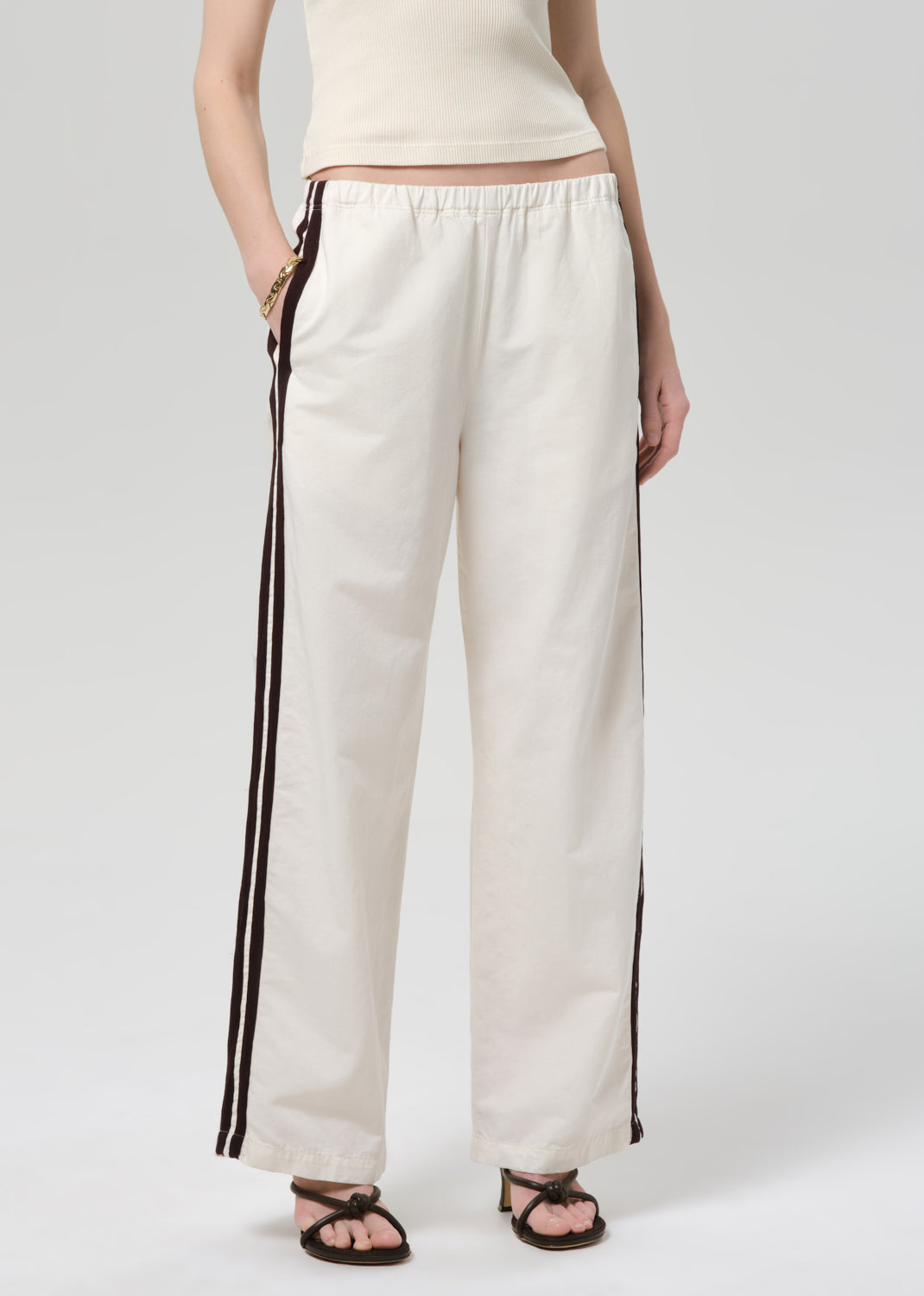 Person wearing a cream tank top and wide-leg pants with stripes on a plain background