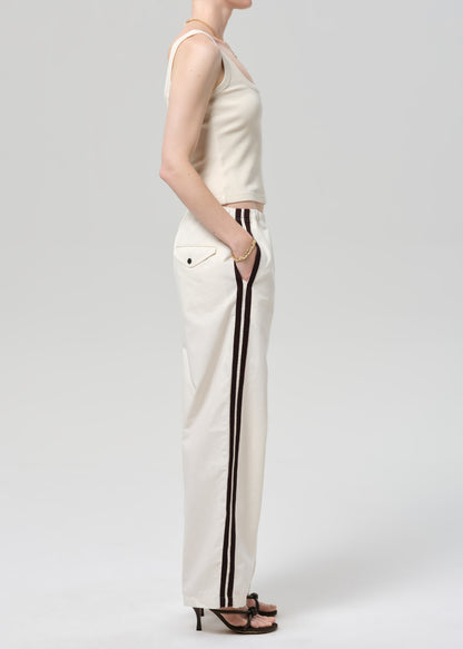 Person wearing a cream tank top and wide-leg pants with stripes on a plain background