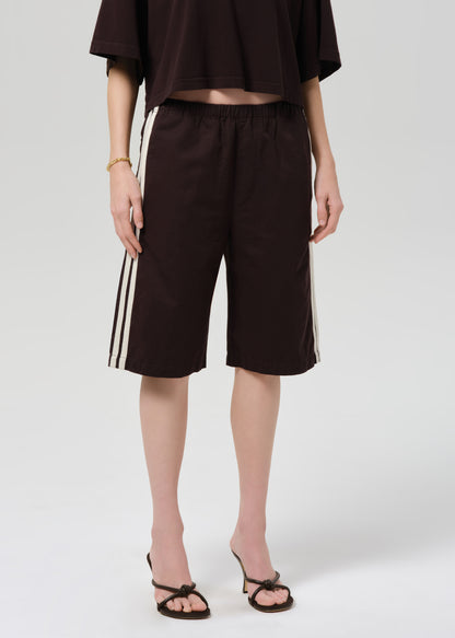 Person wearing a dark brown outfit with shorts on a plain background