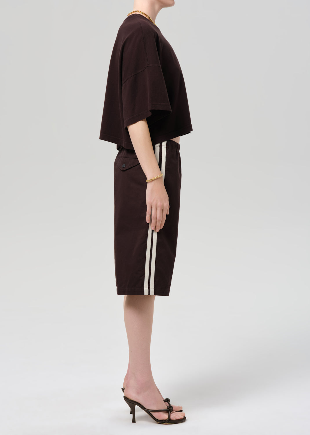 Person wearing a dark brown outfit with shorts on a plain background