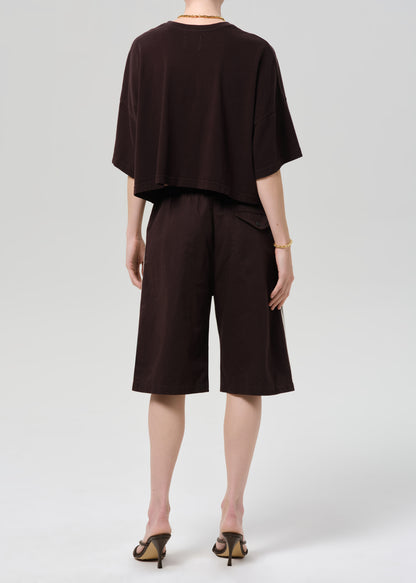 Person wearing a dark brown outfit with shorts on a plain background