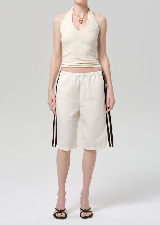 Person wearing a cream-colored halter top and shorts with stripes on a light gray background