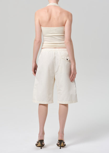Person wearing a cream-colored halter top and shorts with stripes on a light gray background