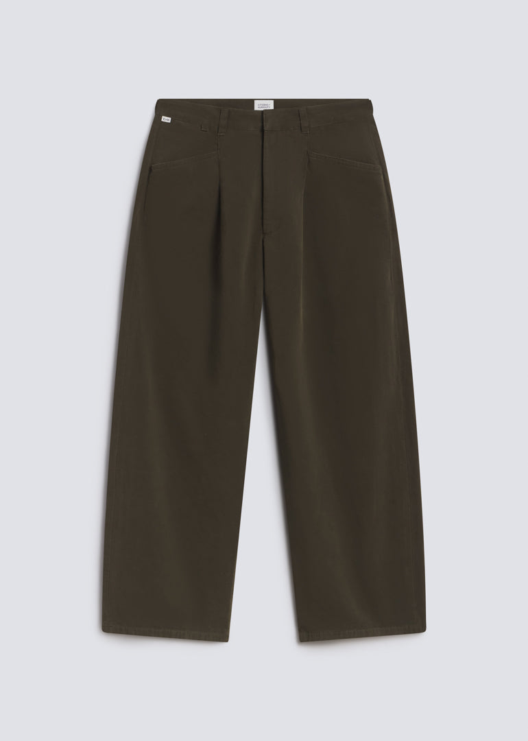 Velha Trouser in Moss, featuring dark olive green fabric, a relaxed wide leg silhouette, front pleats, belt loops, and angled front pockets, front view on a grey background.