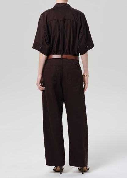 Person wearing a brown shirt and wide-leg pants on a grey background
