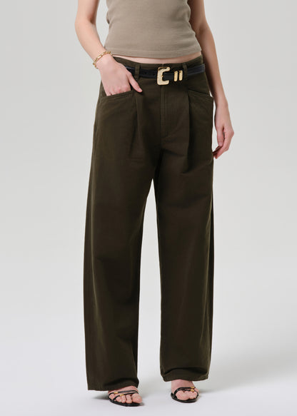 Person wearing brown wide-leg pants with a belt on a grey background
