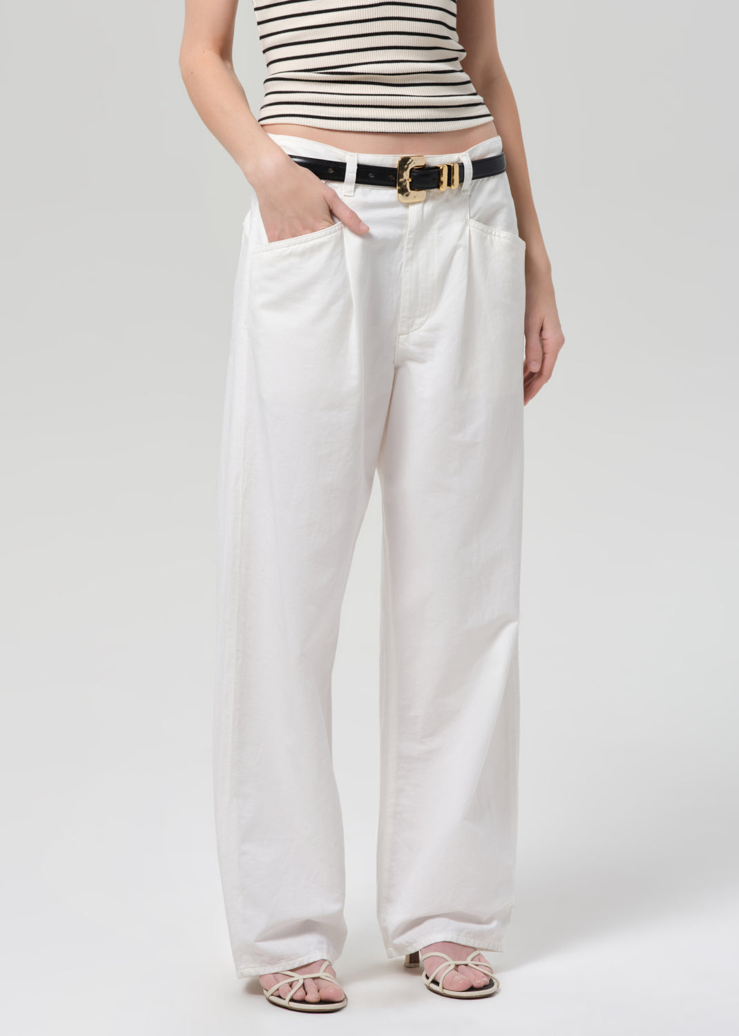 Person wearing a striped top and white wide-leg pants on a plain background