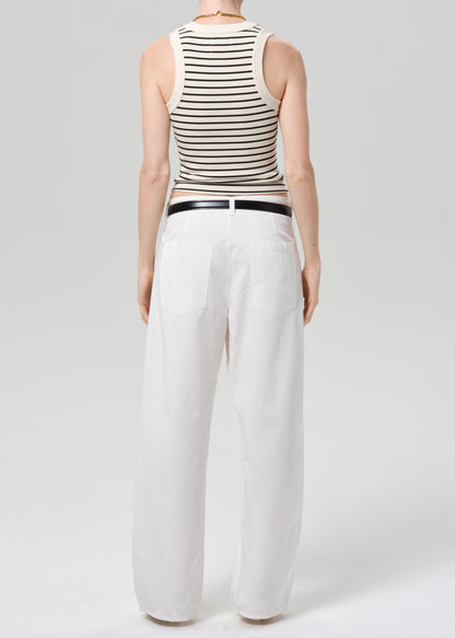 Person wearing a striped tank top and white pants on a plain background