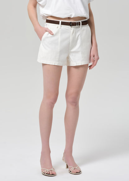 Person wearing a white top and off-white shorts on a plain background
