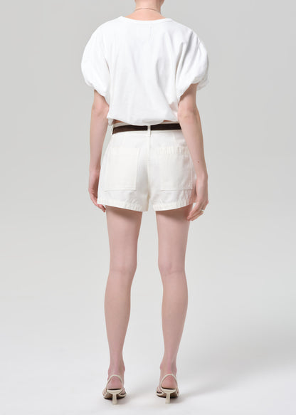 Person wearing a white top and off-white shorts on a plain background