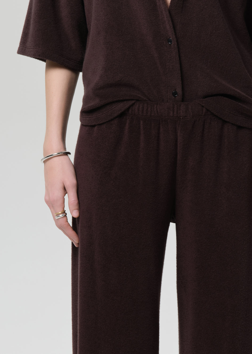 Person wearing a brown terry set on a grey background