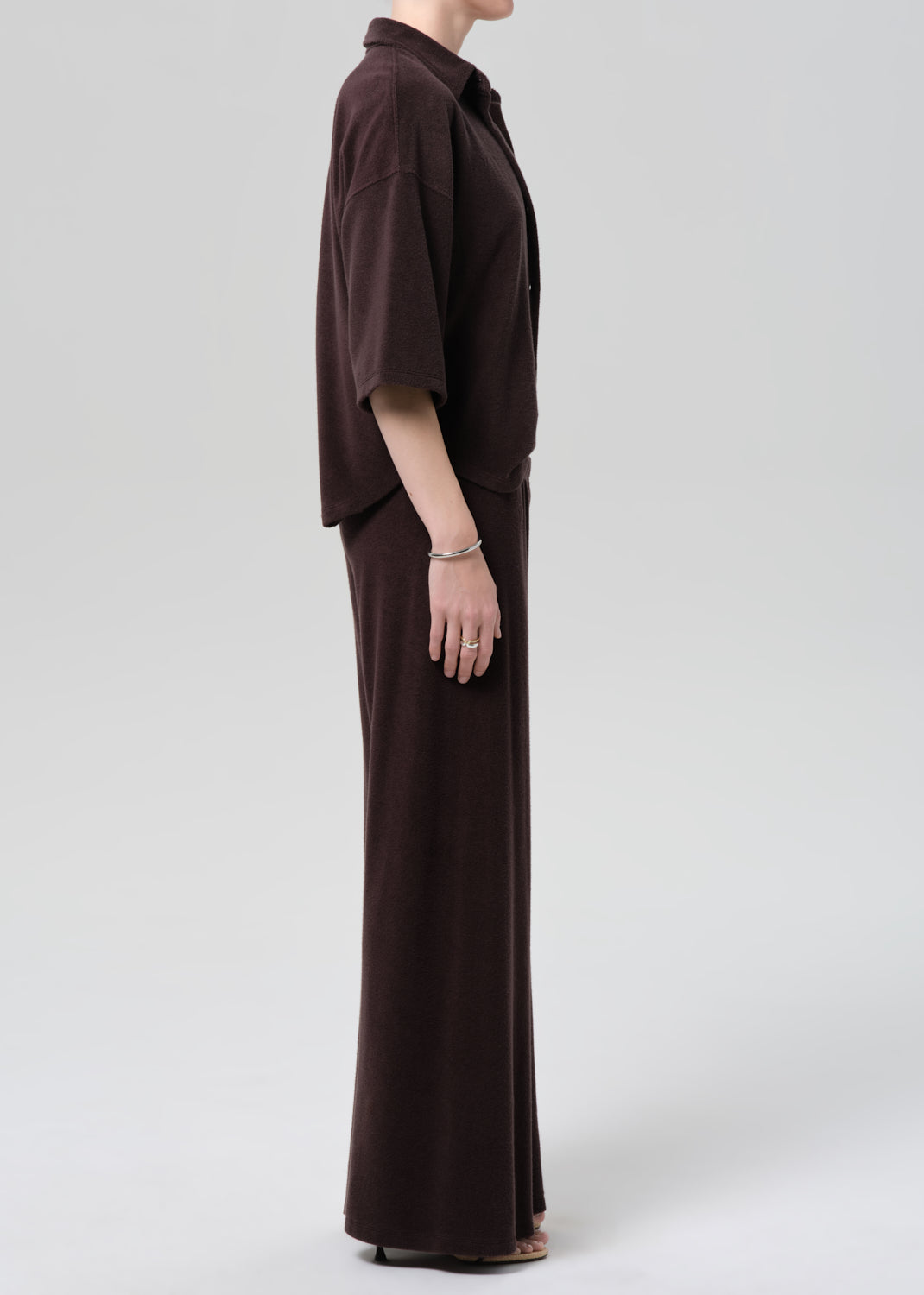Person wearing a brown terry set on a grey background