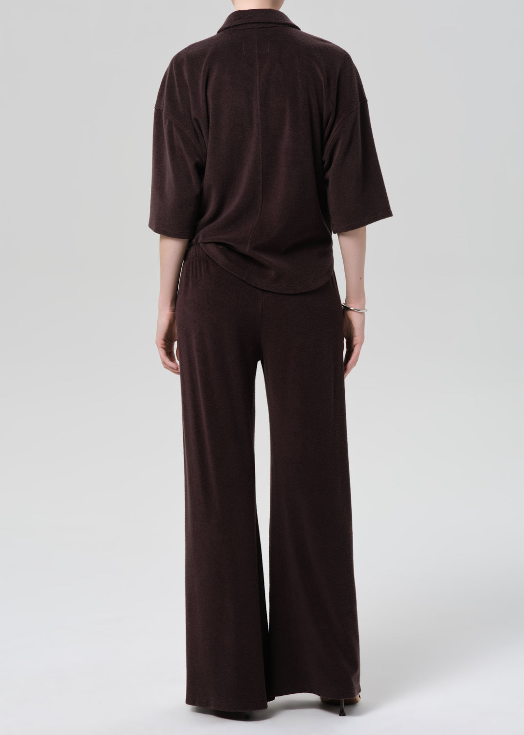 Person wearing a brown terry set on a grey background