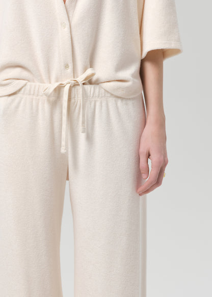Woman wearing a cream terry outfit on a plain background