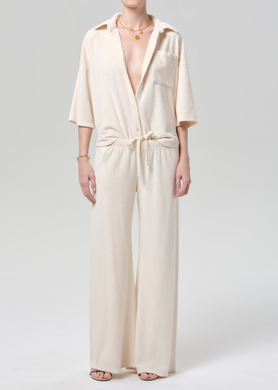Woman wearing a cream terry outfit on a plain background