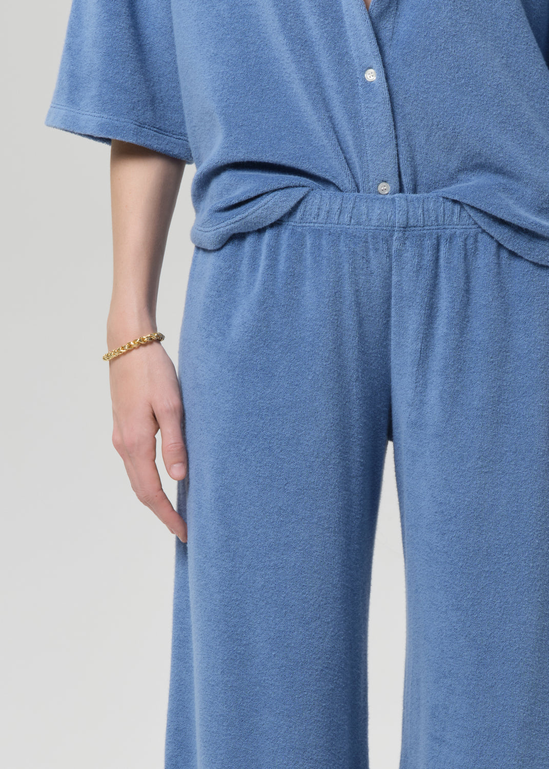 Person wearing a blue terry outfit on a light gray background