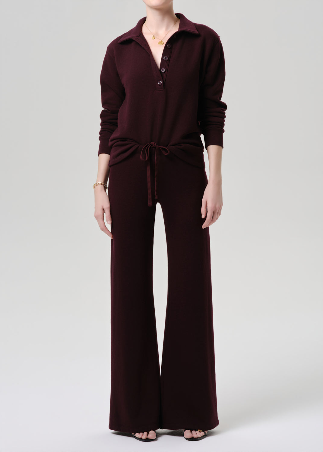 Person wearing a maroon jumpsuit on a grey background